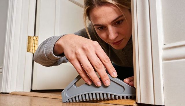 Woman installing door sweep to block drafts and improve home energy efficiency