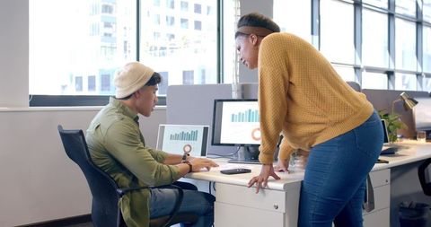 Diverse coworkers collaborating on data charts at modern open-plan office desk