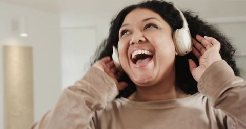Laughing African American Woman Listening to Music with Headphones at Home, Joyful Moment