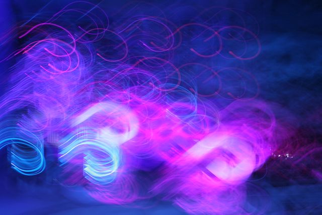 Abstract light trails in vibrant pink and blue create a mesmerizing visual effect. Perfect for use in digital art, backgrounds, design projects, advertising, and presentations. The swirling motion and neon colors add a dynamic and modern touch to any creative work.