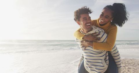 Joyful Couple Having Fun on Beach Piggyback Ride