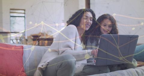 Mother and daughter learning together on couch using laptop with network overlay