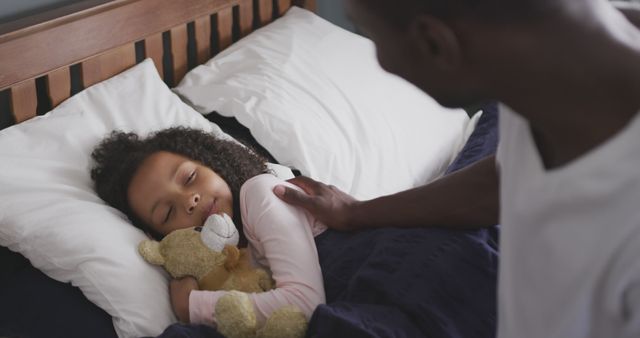Father lovingly checking on his sleeping daughter who is cuddling a teddy bear. Parenthood and family bonding images ideal for use in blogs, parenting websites, social media posts about family life, or advertisements for children's products.