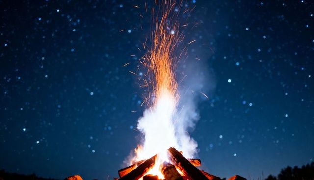 Crackling bonfire under starry sky sending embers sparks and smoke from stacked logs night