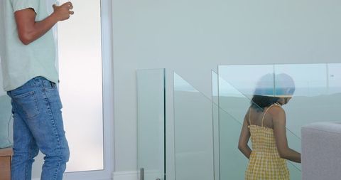 Father Drinking Coffee While Young Woman Descends Modern Staircase