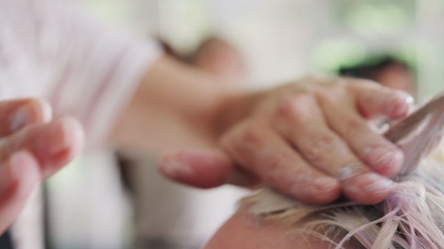 Hands of a male hairstylist skillfully applying hair foam to a female client's hair in a salon environment, emphasizing the care and attention to detail. Ideal for beauty industry promotions, hair care tutorials, or articles on modern hairstyling techniques.