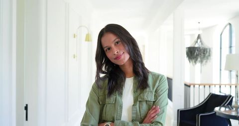 Confident young african american woman standing arms crossed with wristwatch in hallway