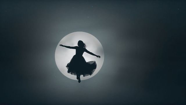 Dancer silhouette floating gracefully before full moon