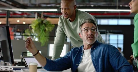 Diverse Team Collaborating around Monitor in Bright Modern Open-Plan Workspace