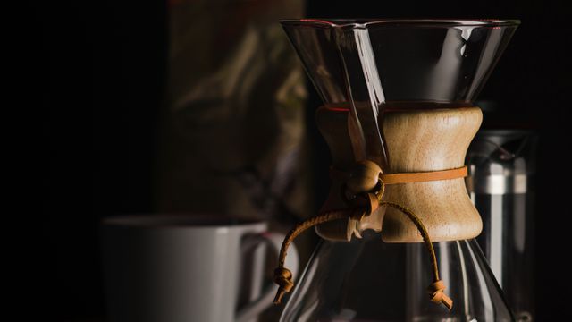 Chemex coffee maker focused on dark background, ideal for emphasizing the beauty of manual brewing. Use in blogs about coffee culture, advertisements for kitchen appliances, or tutorials on making coffee at home.