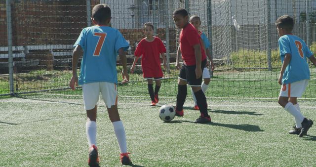 Group of young boys playing an engaging, competitive soccer game in an urban field under clear skies. Ideal for promoting youth sports programs, soccer training camps, outdoor activity advertisements, and healthy lifestyle campaigns.