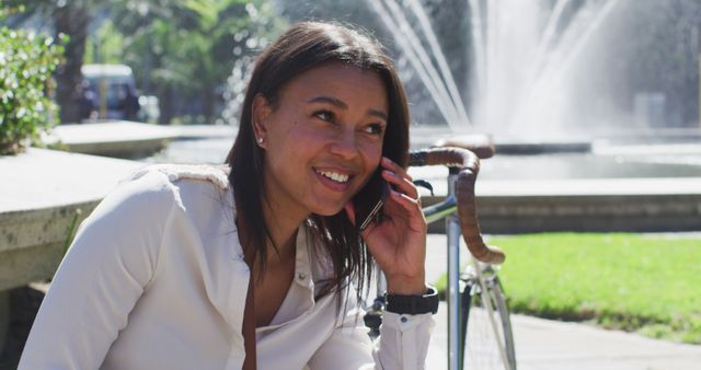 Smiling Woman Talking on Phone Outdoors Near Fountain - Download Free Stock Images Pikwizard.com