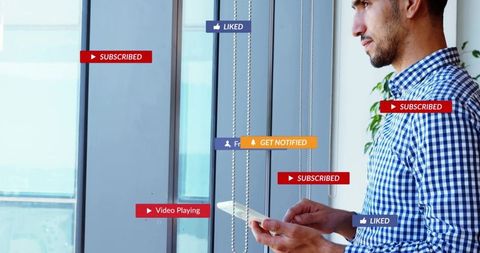 Standing man holding tablet with social media ui badges by office window skyline