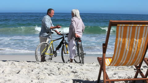 Senior Cyclists Enjoying Conversation by Seaside