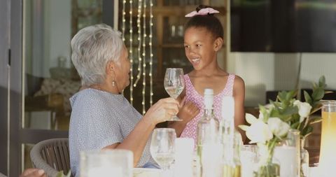 Grandmother and Granddaughter Sharing Toast at Candlelit Multigenerational Family Dinner