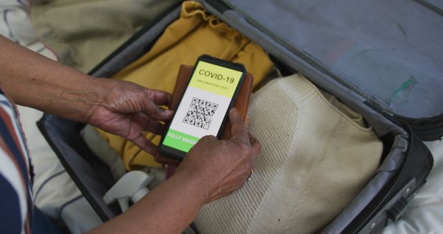 Hand Holding Mobile COVID-19 Vaccination Certificate While Unpacking Suitcase - Download Free Stock Images Pikwizard.com