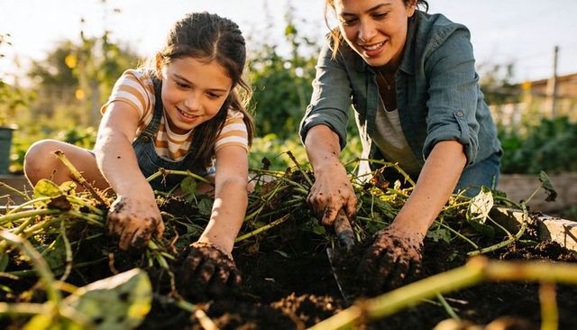 Mother and Daughter Digging Soil Together in Sunlit Raised Garden Bed