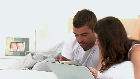 Couple Relaxing in Bed with Tablet Watching Videos