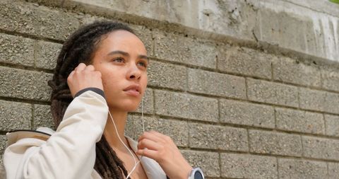 Young Woman with Earphones Against Urban Wall