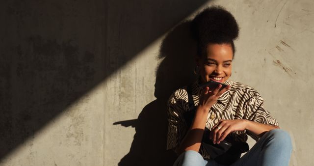 Happy Woman Sitting Against Wall in Sunlight with Urban Background - Download Free Stock Images Pikwizard.com