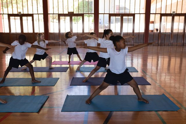 Front view of schoolkids doing yoga on a yoga mat in school gymnast 