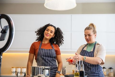 Diverse friends filming culinary video with ring light in modern kitchen