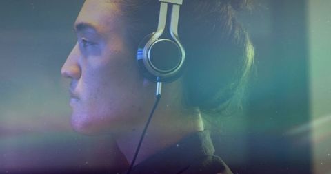 Asian Man Wearing Silver Headphones in Ambient Studio Light