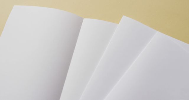 Close-up of four blank white sheets fanned out against a neutral background. Ideal for use in presentations, marketing materials, or website backgrounds to emphasize concepts of simplicity, cleanliness, and potential uses for blank canvas.