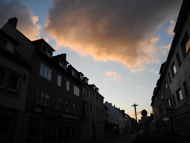 Silhouetted view of urban buildings against a dramatic sky during dusk. This perspective showcases the quiet atmosphere of an evening in the city, emphasizing the play of light and shadow. Suitable for use in projects related to urban life, architecture, mood setting, and time transitions.