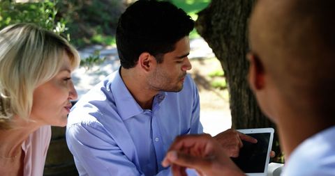 Friends Relaxing at Restaurant Outdoor Table Discussing Over Tablet