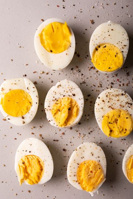 Halved boiled eggs sprinkled with spices and seasoning on a light background. Ideal for illustrating healthy eating, protein-rich diets, breakfast ideas, or simple snacks. Perfect for food blogs, nutrition articles, and recipe websites.