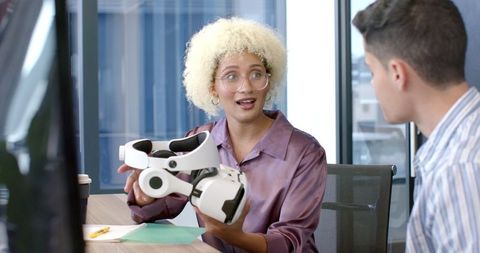 Woman presenting vr headset to colleague in modern office setting