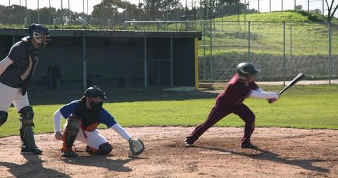 Baseball players in intense game action at batting cage