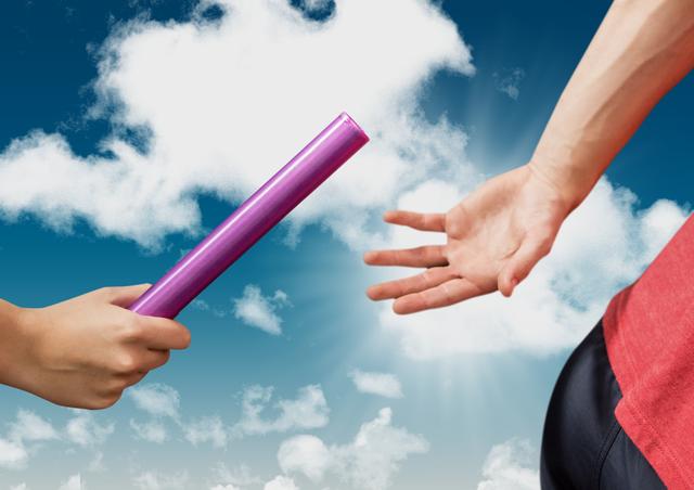 Hands of two runners seen passing a baton during a relay race with sky and clouds in the background. Ideal for use in topics concerning teamwork, athletic competitions, sportsmanship, and relay race events.