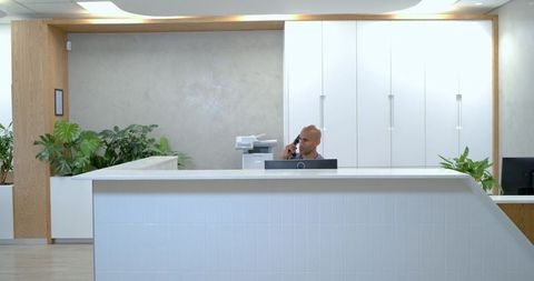 African American Receptionist Talking on Corded Phone at Modern Minimalist Front Desk