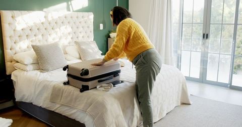 Woman Packing Suitcase on Luxury Bed in Bright Cozy Bedroom