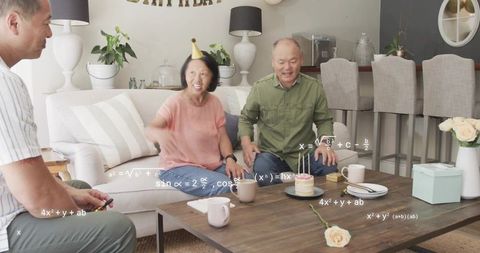 Family celebrating birthday at home laughing by coffee table with cake and playful math graphics
