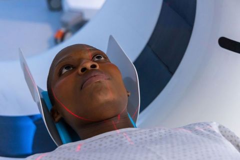 African woman undergoing mri scan wearing head coil with red laser alignment