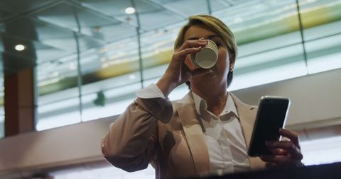 Businesswoman at Airport Espresso while Using Smartphone
