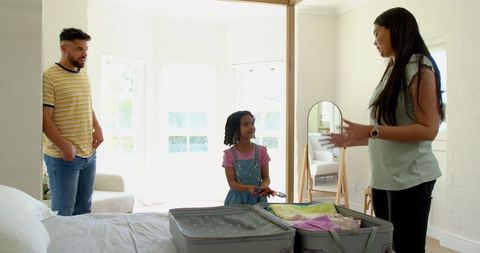 Diverse Family Packing Suitcase in Cozy Bright Bedroom