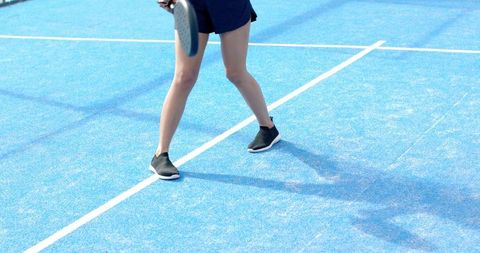 African american woman playing pickleball on blue court holding paddle outdoor lifestyle
