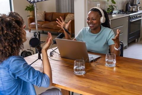 African american women hosting energetic home podcast recording laptop and microphone