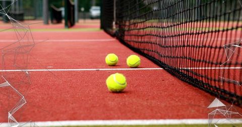 Tennis Balls on Red Clay Court Beside Net