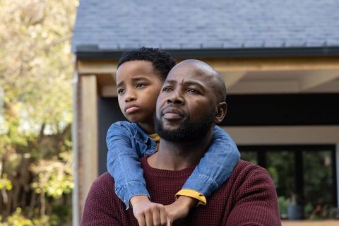 African american father and son sharing quiet reflective moment on front porch