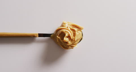 Peanut Butter Spread on Knife over White Surface