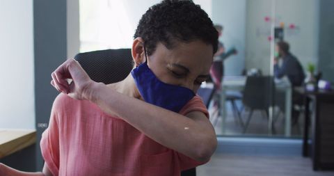 Woman Practicing Sneezing Etiquette with Face Mask in Office