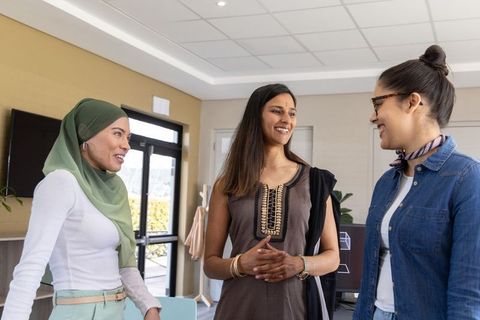 Diverse professional women collaborating and smiling in bright modern office workplace