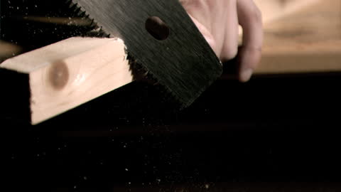 Sawing Wooden Board in Close-Up with Flying Dust Particles