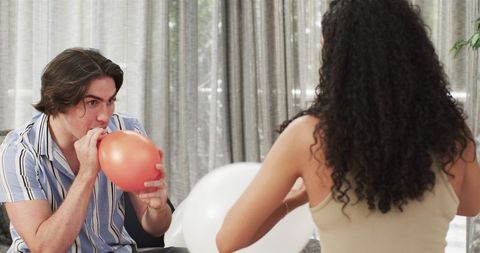 Couple Blowing Balloons for Birthday Celebration at Home