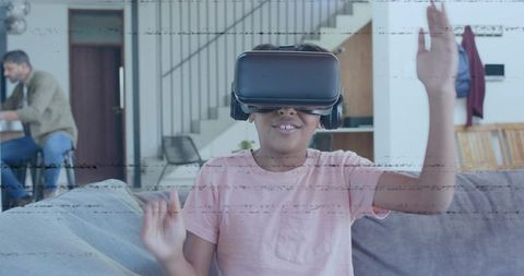 Child Wearing VR Headset Playing on Sofa While Parent Using Smartphone at Home
